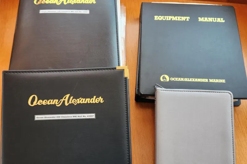 Wandering Bear Yacht Photos Pics Manuals and folders for 2001 Ocean Alexander Classico yacht on wooden surface.