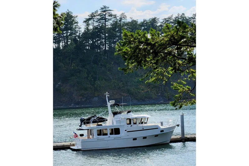 Wandering Bear Yacht Photos Pics 2001 Ocean Alexander Classico yacht docked by a scenic forested shoreline.