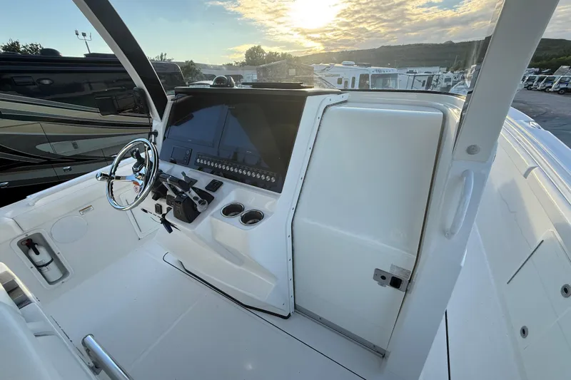 Yacht Photos Pics 2018 Edgewater 370CC boat helm with steering wheel, control panel, and cup holders at sunset.