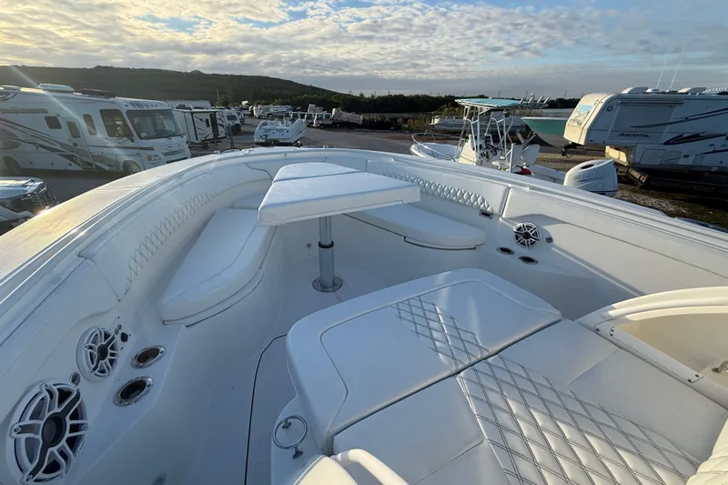  Yacht Photos Pics 2018 Edgewater 370CC boat interior with white seating and table, parked near RVs under a cloudy sky.