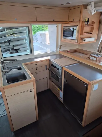 Chapter Two Yacht Photos Pics Modern kitchen interior of 2014 Lagoon 450 catamaran with wood cabinetry and appliances.