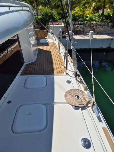 Chapter Two Yacht Photos Pics 2014 Lagoon 450 yacht deck with teak flooring and coiled rope, docked by lush greenery.