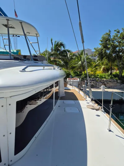 Chapter Two Yacht Photos Pics 2014 Lagoon 450 catamaran docked, surrounded by tropical trees under clear blue sky.