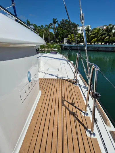 Chapter Two Yacht Photos Pics 2014 Lagoon 450 yacht deck with wooden flooring, docked by tropical greenery.