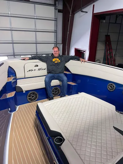  Yacht Photos Pics Man sitting on 2015 Nor-Tech 340 Sport Center Console boat in a garage.