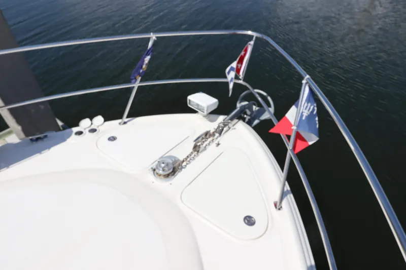  Yacht Photos Pics Bow of 2004 Sea Ray 420 Sundancer with flags and anchor chain on calm water.