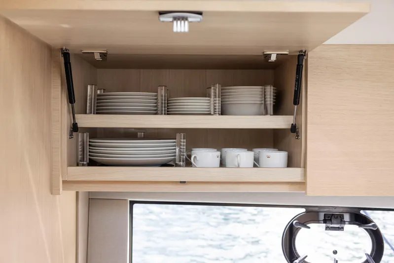 V40188 Yacht Photos Pics Open cabinet in 2024 Princess V40 yacht with neatly arranged dishes and cups.