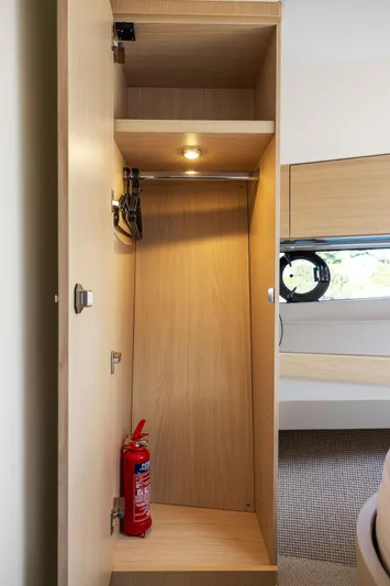 V40188 Yacht Photos Pics 2024 Princess V40 yacht interior closet with fire extinguisher and wooden shelves.