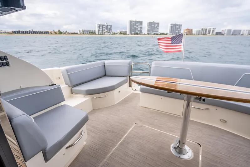 Pier Pressure Yacht Photos Pics Carver C52 Coupe 2017 yacht with seating area and table, American flag in background.
