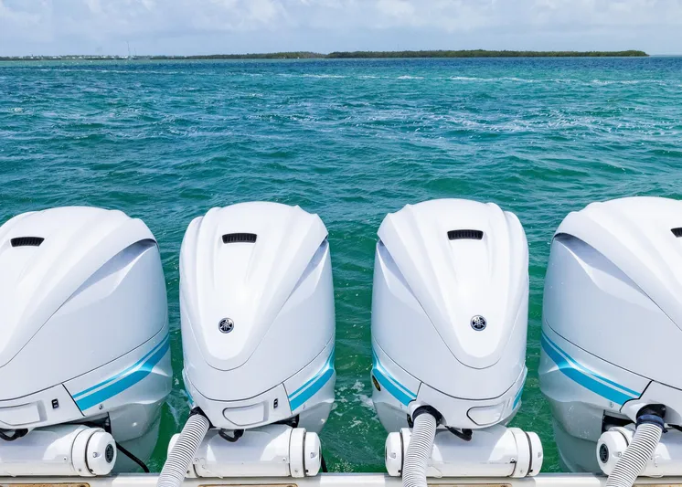  Yacht Photos Pics Four powerful outboard motors on a 2021 HCB 53 Sueños boat, ocean backdrop.