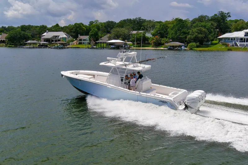  Yacht Photos Pics 2020 Invincible 39 Open Fisherman cruising on a scenic lake with lush greenery.
