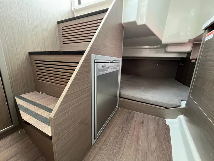  Yacht Photos Pics 2023 Beneteau Flyer 9 SUNdeck interior with wood finish, compact fridge, and cozy sleeping area.
