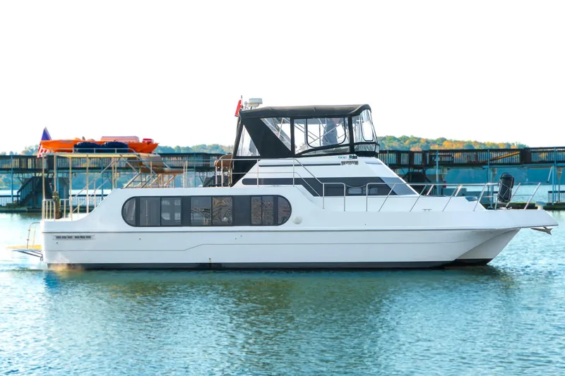 Jolly Roger II Yacht Photos Pics 1997 Harbor Master Stolkraft boat docked on calm water, featuring sleek design and spacious cabin.