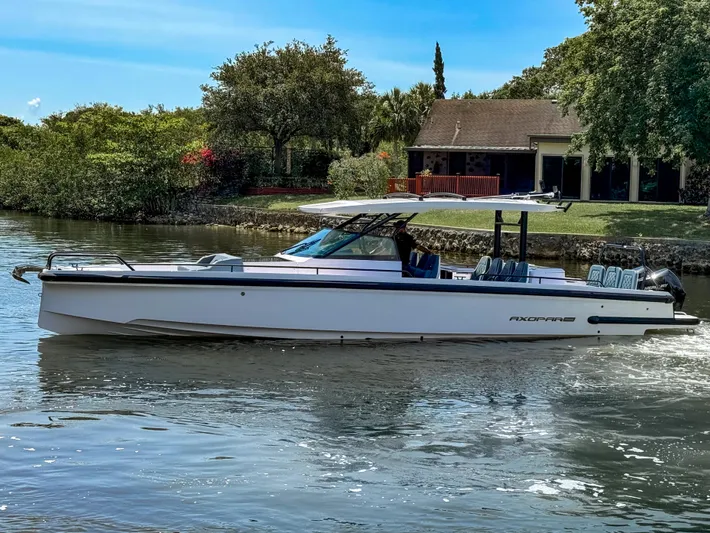  Yacht Photos Pics 2024 Axopar 37 Sun Top boat cruising on a serene river near a house.