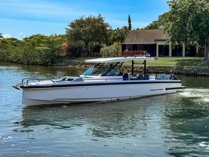  Yacht Photos Pics 2024 Axopar 37 Sun Top cruising on a serene river near a house.