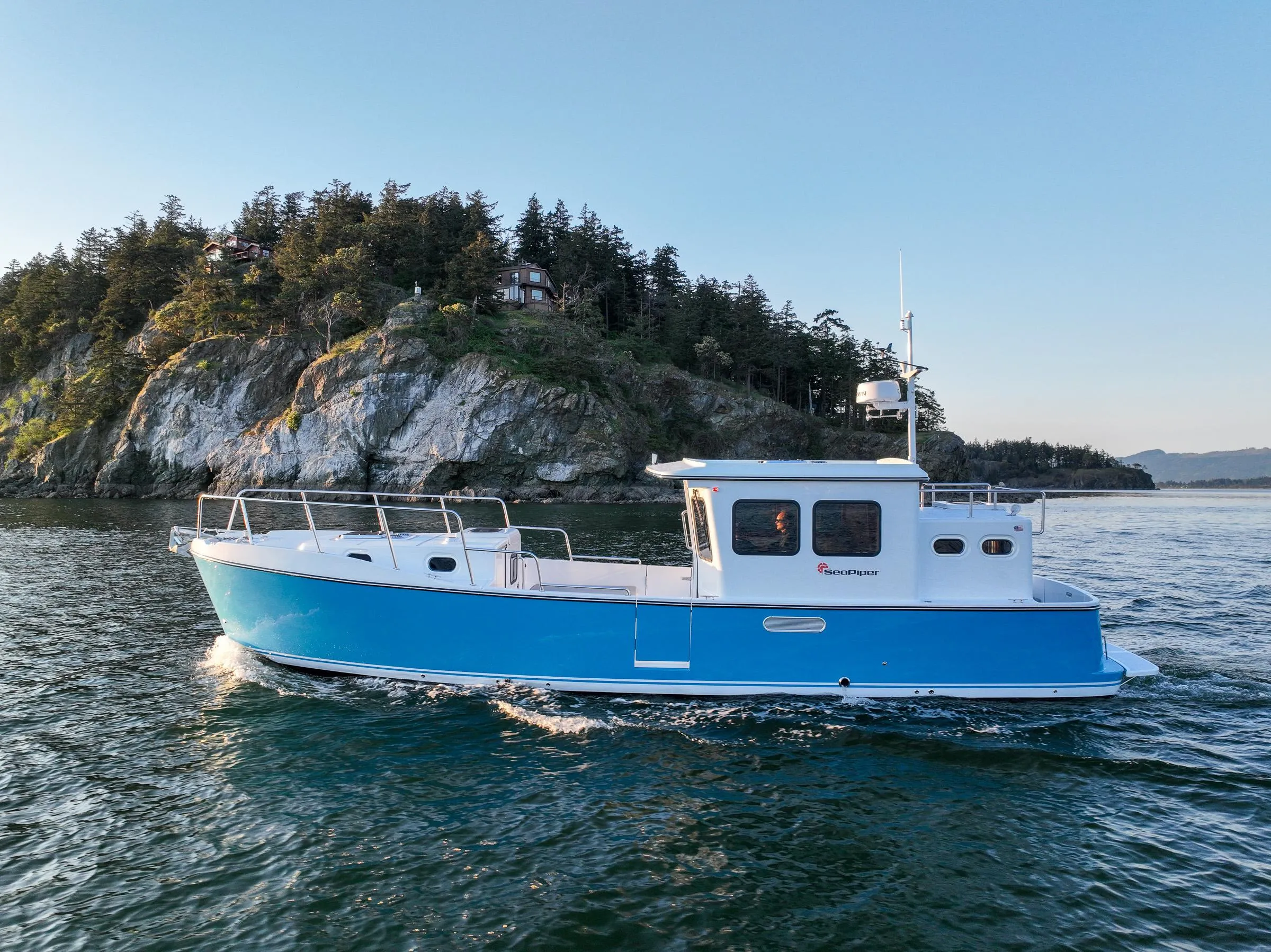 2025 SeaPiper 37 boat cruising near a rocky shoreline with trees in the background.