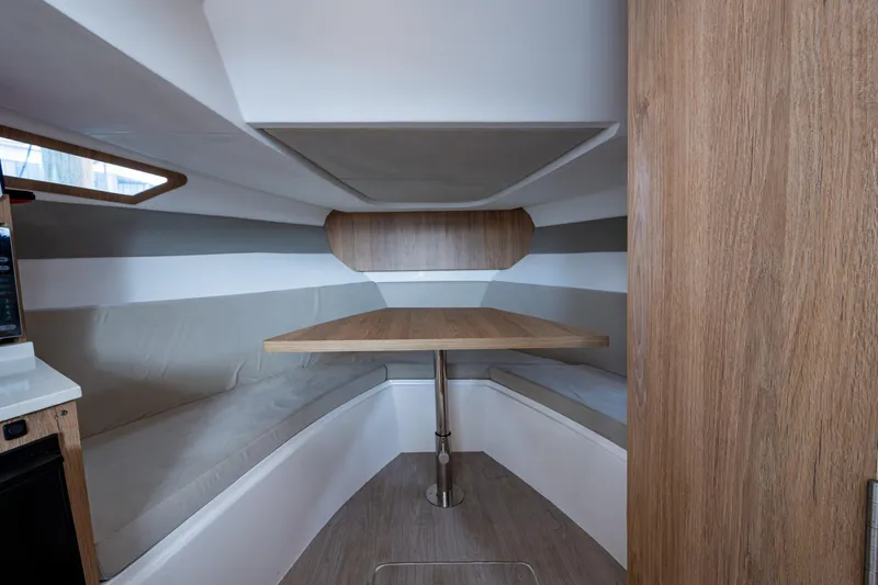 Xuru Yacht Photos Pics Interior of 2023 NX 340 boat with wooden table and cushioned seating.