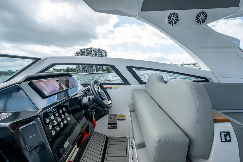 Xuru Yacht Photos Pics 2023 NX 340 boat interior with modern dashboard and seating, overlooking waterfront buildings.
