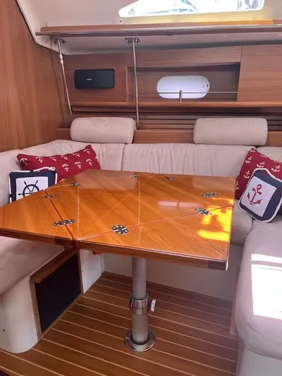 Rita Gale Yacht Photos Pics Interior of 2012 Catalina 355 sailboat with wooden table and nautical-themed cushions.