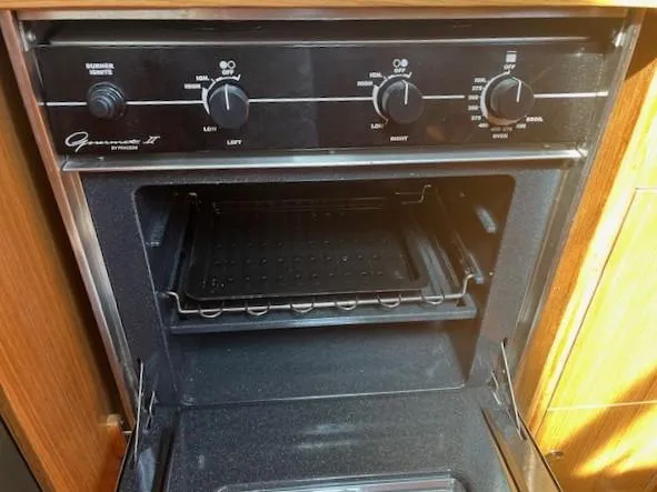 Rita Gale Yacht Photos Pics Catalina 355 2012 oven with control knobs and open door in a wooden kitchen setting.