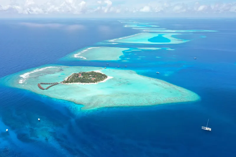 Vitalia II Yacht Photos Pics Aerial view of tropical island with 2003 Multiplast High Performance Catamaran in turquoise waters.