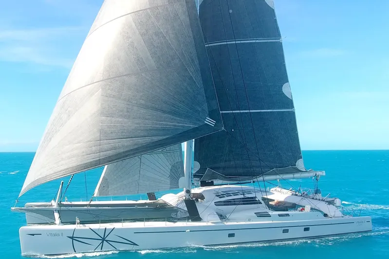 Vitalia II Yacht Photos Pics High-performance 2003 Multiplast catamaran sailing on clear blue ocean waters.