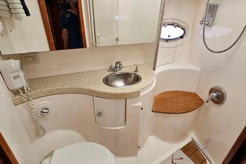  Yacht Photos Pics Luxurious 2005 Regal Commodore 4260 yacht bathroom with sink, shower, and wooden seat.