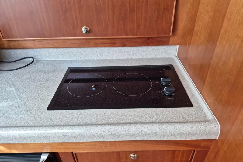  Yacht Photos Pics 2004 Riviera 4000 Offshore yacht kitchen with electric stovetop and wooden cabinetry.