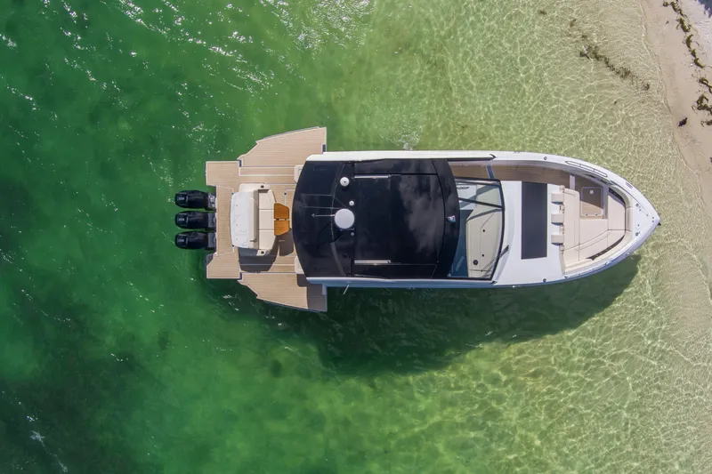  Yacht Photos Pics Aerial view of 2026 Cruisers Yachts 50 GLS on clear green water near sandy shore.