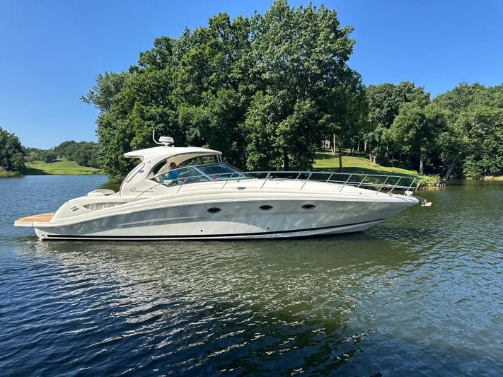  Yacht Photos Pics 2005 Sea Ray 420 Sundancer yacht cruising on a serene lake with lush green trees.