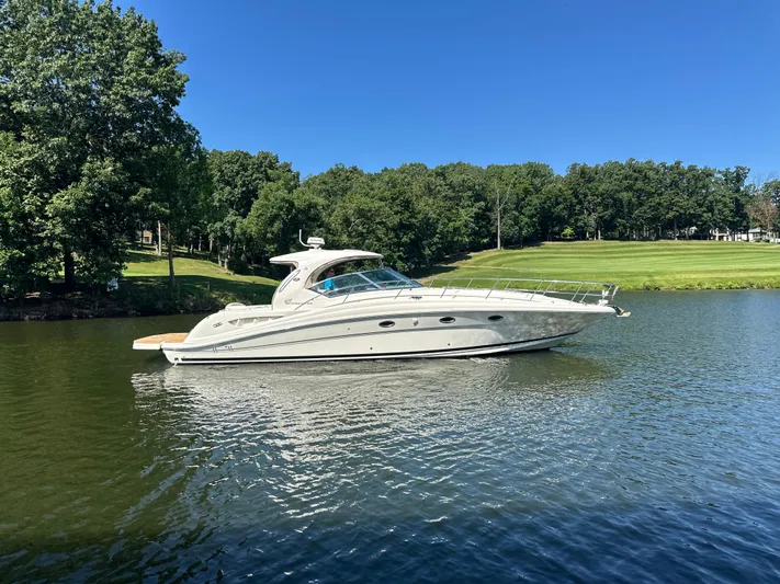  Yacht Photos Pics 2005 Sea Ray 420 Sundancer yacht cruising on a serene lake under a clear blue sky.