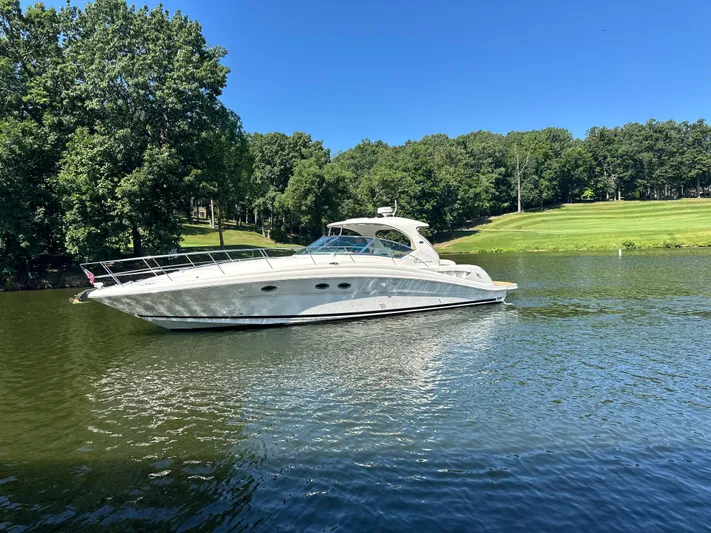  Yacht Photos Pics 2005 Sea Ray 420 Sundancer yacht on a serene lake with lush green trees.