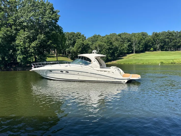  Yacht Photos Pics 2005 Sea Ray 420 Sundancer yacht on a serene lake with lush green surroundings.