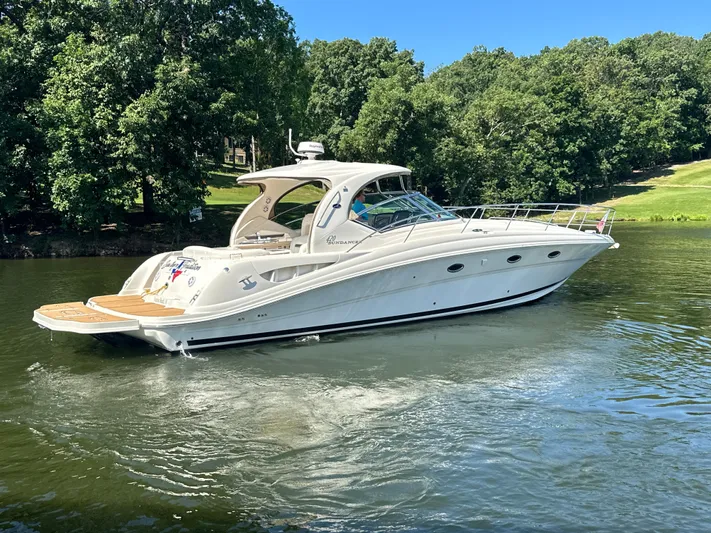  Yacht Photos Pics 2005 Sea Ray 420 Sundancer yacht cruising on a serene lake with lush green trees.