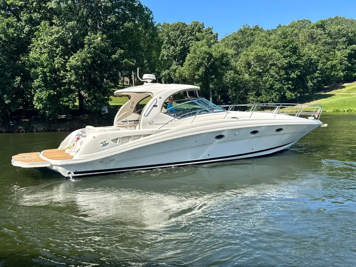  Yacht Photos Pics 2005 Sea Ray 420 Sundancer yacht cruising on a serene lake with lush green trees.