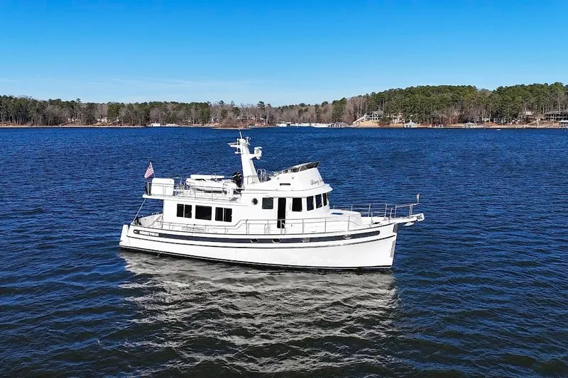 Ring Leader Yacht Photos Pics 2007 Nordic Tug 54 cruising on a serene lake with forested shoreline.