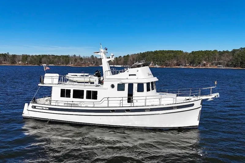 Ring Leader Yacht Photos Pics 2007 Nordic Tug 54 cruising on a serene lake under a clear blue sky.