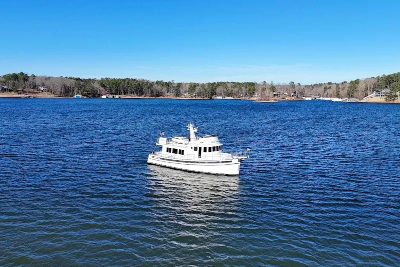 Ring Leader Yacht Photos Pics 2007 Nordic Tug 54 cruising on a serene lake under a clear blue sky.