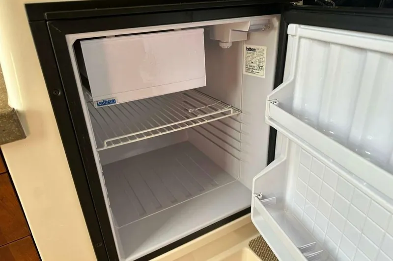  Yacht Photos Pics Open refrigerator inside 2014 Grady-White Express 330 boat, showing empty shelves and door compartments.