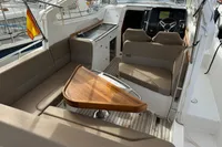 Interior of 2022 Nimbus W9 boat with seating, wooden table, and steering console.