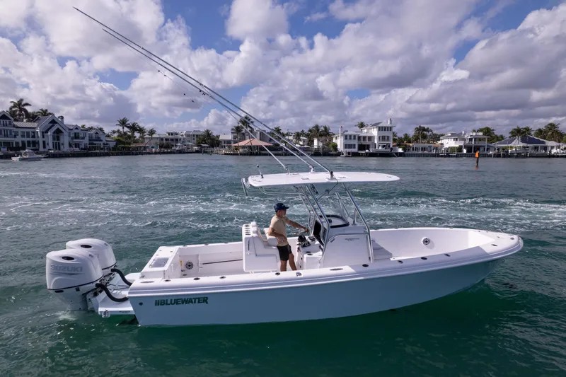  Yacht Photos Pics 2024 Bluewater 2550 boat cruising on a scenic waterfront with modern homes.