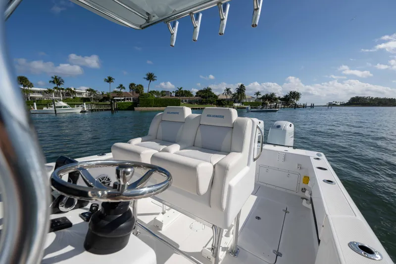  Yacht Photos Pics 2024 Bluewater 2550 boat with luxurious seating, steering wheel, and scenic waterfront view.