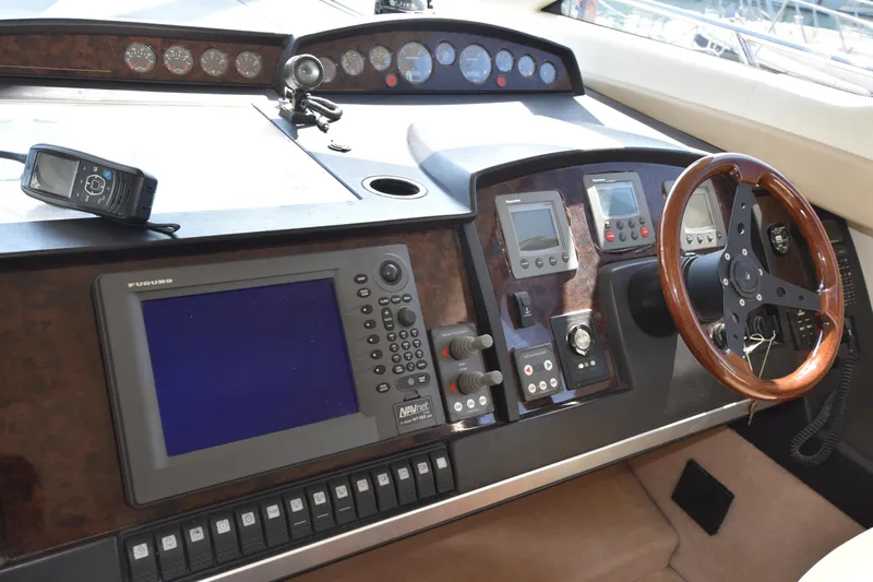 Spirit Bear Yacht Photos Pics Control panel of a 2006 Princess 50 yacht with navigation equipment and wooden steering wheel.