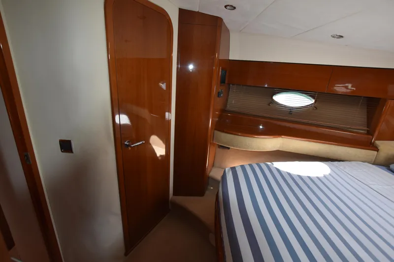 Spirit Bear Yacht Photos Pics Luxurious cabin interior of 2006 Princess 50 yacht with striped bedding and wooden finishes.