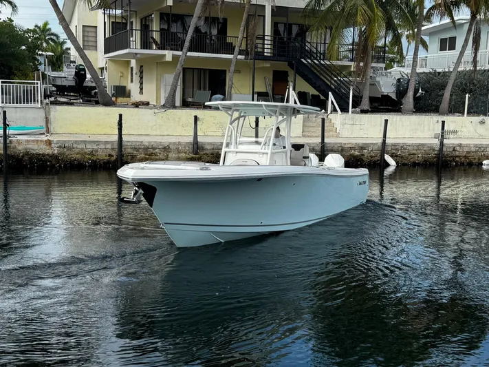  Yacht Photos Pics 2022 Sailfish 290 CC boat on calm water near a waterfront house.