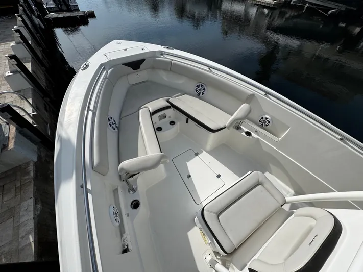  Yacht Photos Pics 2022 Sailfish 290 CC boat interior with white seating and speakers, docked by calm water.