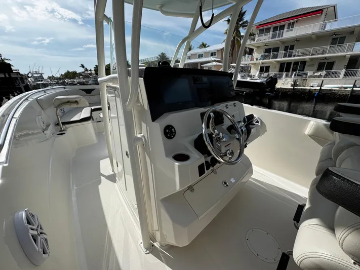  Yacht Photos Pics 2022 Sailfish 290 CC boat interior with steering console, docked near waterfront homes.