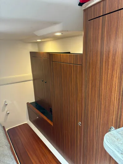  Yacht Photos Pics 2018 Pursuit OS 355 Offshore cabin interior with wood paneling and storage cabinets.