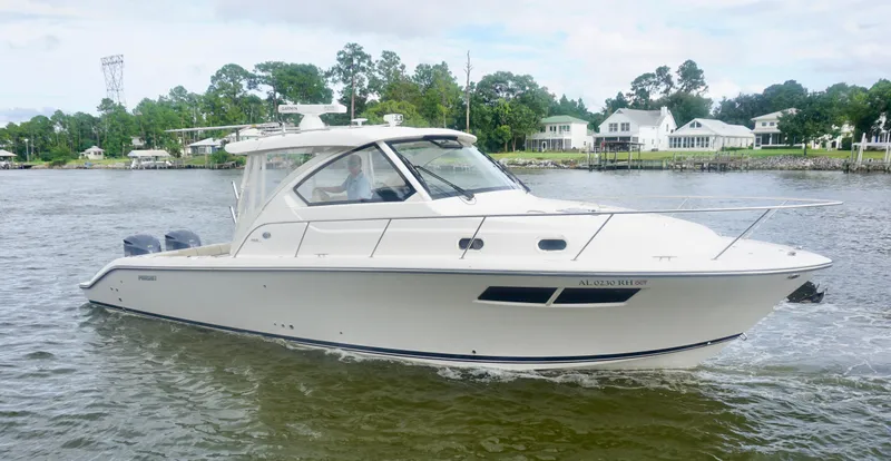  Yacht Photos Pics 2018 Pursuit OS 355 Offshore boat cruising on a calm river near waterfront homes.