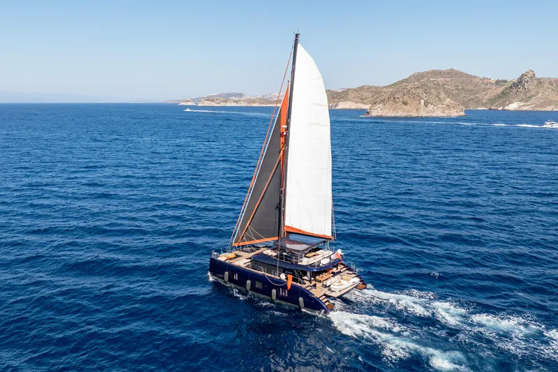  Yacht Photos Pics 2024 Sunreef 60 Eco sailing in open sea near rocky coastline.